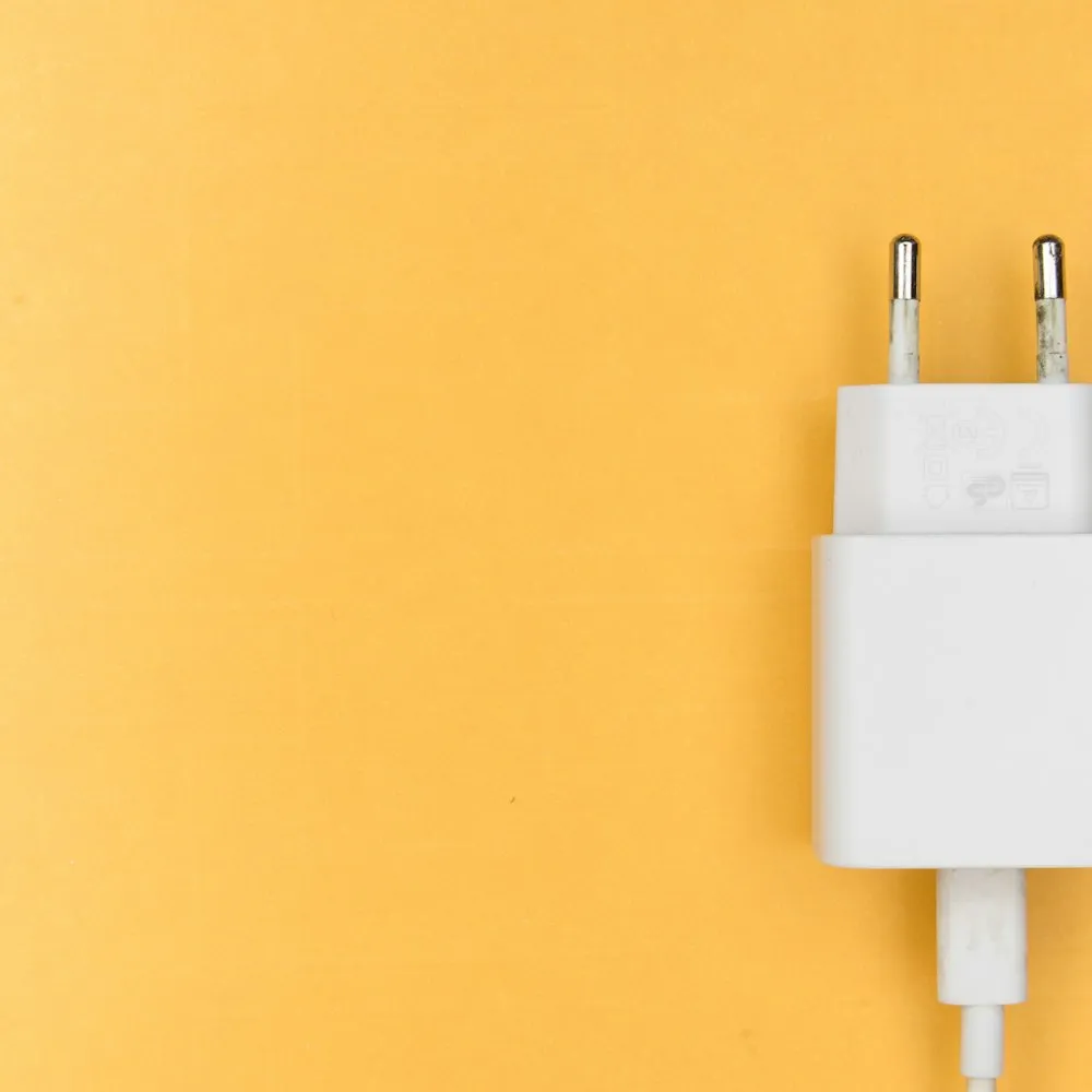 Chargeur secteur blanc branché sur un mur jaune